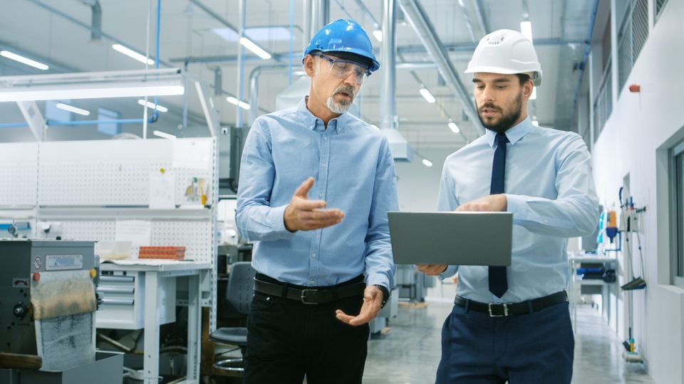 Abteilungsleiter hält Laptop und bespricht Produktdetails